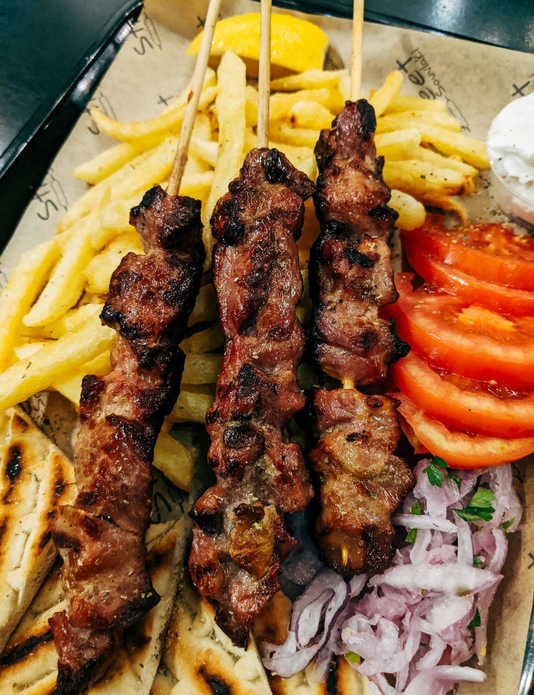 Souvlaki vom Spieß mit Pita, Pommes und roten Zwiebeln