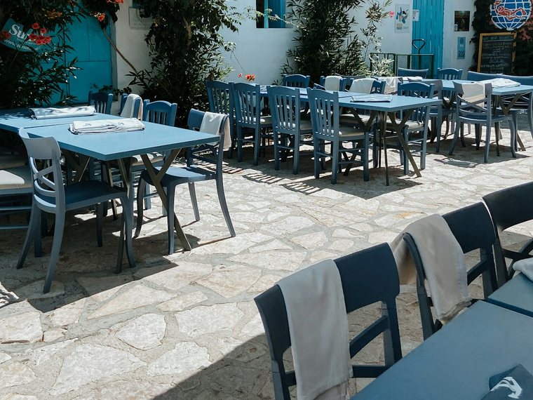 Terrasse einer Taverne mit blauen Tischen und Bougainvillea